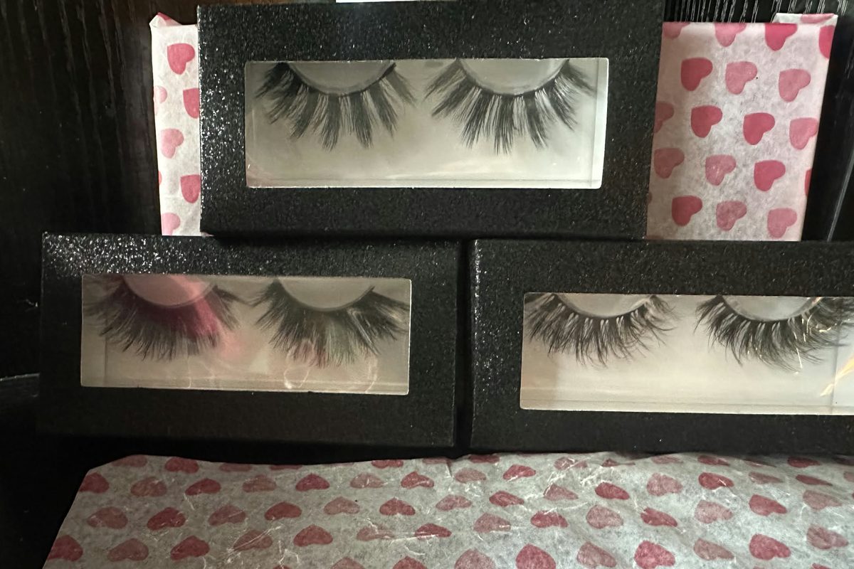 Three pairs of lashes in black glitter window boxes stacked on pink heart tissue paper